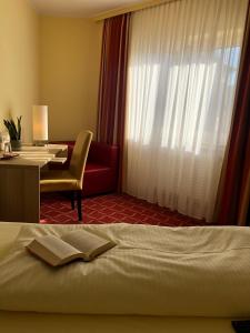 a hotel room with a bed and a desk and a window at Montana Hotel Köln-Bonn Airport in Troisdorf