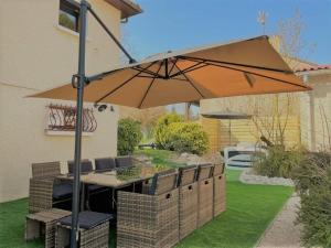 una mesa y sillas bajo una sombrilla en un patio en Gîte du Lapin Bleu en Coole