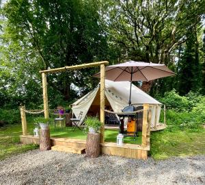 a tent with a table and an umbrella at Garden County Glamping in Newtown Mount Kennedy