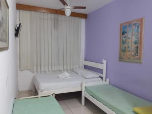 a small room with two beds and a window at Chale Mineiro Hostel & Pousada in Belo Horizonte