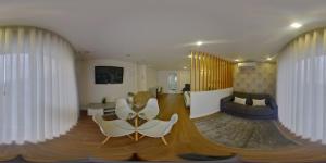 a living room with white chairs and a table at Villa Tavares Suítes in Arouca