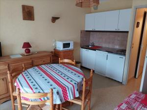 a small kitchen with a table and a microwave at Studio-cabine Résidence les Rennes in Prémanon