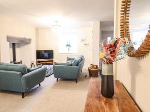 a living room with chairs and a vase with flowers on a table at 7 Tai Oakeley in Blaenau-Ffestiniog