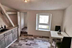 ヴィルヘルムスハーフェンにある1 ZKB DG Ferienwohnung - Direkt am Kurpark - Zentrale Lageのキッチン(シンク、テーブル付)、窓が備わります。 +5枚の写真