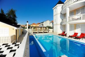 a swimming pool with red chairs next to a house at Apartments Villa Zlatko in Zadar