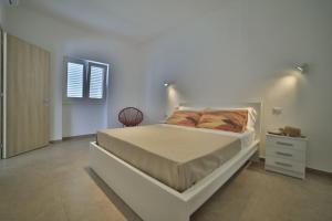 um quarto branco com uma cama e uma cómoda em GIARO' APARTMENTS em Porto Cesareo
