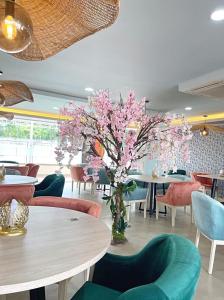 un restaurante con mesas y sillas y un árbol con flores rosas en Hotel Campestre Nala, en Palmira