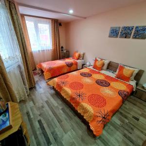 sypialnia z 2 łóżkami i pomarańczowymi kołdrami w obiekcie Fema Guest House w Bałcziku