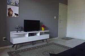 Braga Apartamento Temporada Maceió في ماسيو: غرفة معيشة مع تلفزيون بشاشة مسطحة على خزانة بيضاء