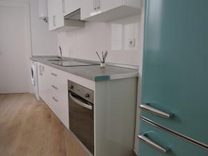 uma cozinha com armários brancos e um frigorífico azul em Apartamento Garcar em Múrcia