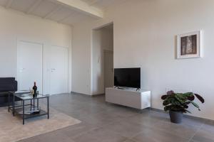 sala de estar con TV de pantalla plana en una pared blanca en Casa Raffaello en San Miniato