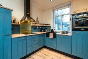 eine blaue Küche mit blauen Schränken und einem Fenster in der Unterkunft Verwalter Haus Apartment 2 in Bad Segeberg