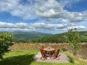a table and chairs on a patio with a view at Pant Llwyd Farm in Llangynidr