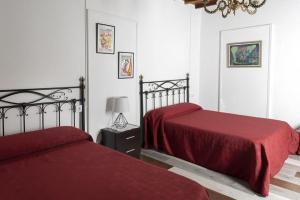 een slaapkamer met 2 bedden met rode lakens en een lamp bij A Pousa Pensión rural (Camino de Santiago Sanabrés) in Armariz