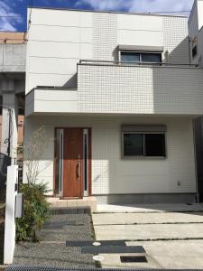 una casa di mattoni bianchi con una porta marrone di Nara Guesthouse Kaede a Nara