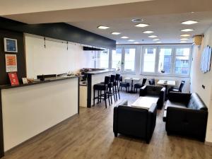 a waiting room with black chairs and a bar at Adler Hotel Frankfurt in Frankfurt/Main