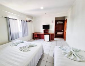 ヴァールゼア・グランデにあるCerrados Park Hotelのベッド2台とテレビが備わるホテルルームです。