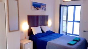 Un dormitorio con una cama azul y una ventana en AREA PLAYA VIVEIRO APARTAMENTS , XOVE, en Jove (Xove)