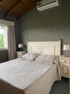 1 dormitorio con 1 cama blanca grande y 2 mesitas de noche en Las Calandrias de Tandil en Tandil