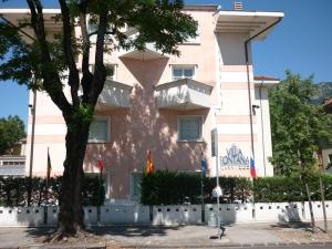 een roze gebouw met een boom ervoor bij Hotel Garnì Villa Fontana in Trento