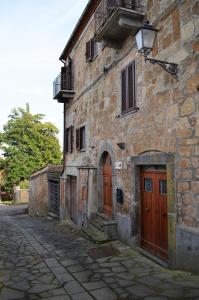 un antiguo edificio de piedra con puertas de madera en una calle en Il giardino di Elena, en Bagnoregio