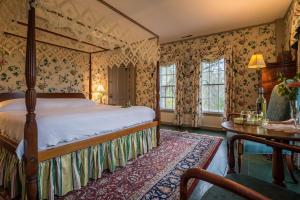 a bedroom with a bed and a table and windows at Inn at Valley Farms in Walpole