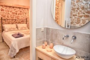 a bathroom with a sink and a bed and a mirror at Villa Markezinis in Lákones
