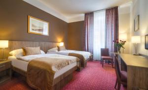 a hotel room with two beds and a desk at Hotel Harmony in Prague