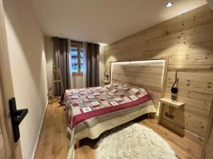 a bedroom with a bed and a wooden wall at BOREAL Bel appartement village et pistes in La Clusaz