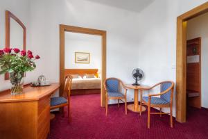 a hotel room with a table and chairs and a bed at Hotel Harmony in Prague