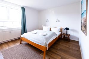 a white bedroom with a bed and a window at Wunderschöne Ferienwohnung mit Feldblick und Balkon (2022 renoviert), mit kostenlosem Wlan und Strandfahrrad, Haustiere erlaubt in Börgerende-Rethwisch