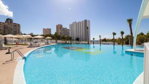 a large blue swimming pool with a city in the background at Sunset Waves Benidorm by Mar Holidays in Benidorm