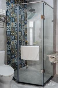 a bathroom with a glass shower with a toilet at La Playa Ha Long Hotel in Ha Long