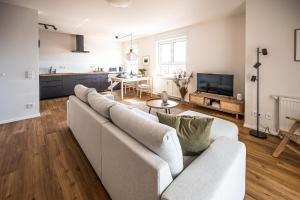 a living room with a white couch and a kitchen at Wunderschöne Ferienwohnung mit Feldblick und Balkon (2022 renoviert), mit kostenlosem Wlan und Strandfahrrad, Haustiere erlaubt in Börgerende-Rethwisch