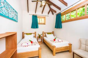 
a bedroom with two beds and a window at Hotel Casa Merlin in Puerto Viejo
