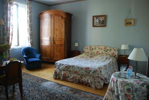 een slaapkamer met een bed, een kast en een tafel bij Château Le Baudou in Coutras