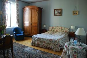 a bedroom with a bed and a cabinet and a table at Château Le Baudou in Coutras