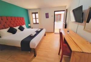a bedroom with a bed and a desk with a television at Jardines de Luz in San Cristóbal de Las Casas