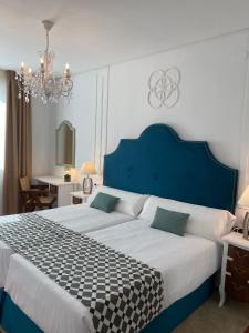 um quarto com uma cama grande e uma cabeceira azul em Hotel Derby Sevilla em Sevilha