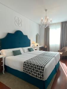 um quarto com uma cama grande e um lustre em Hotel Derby Sevilla em Sevilha