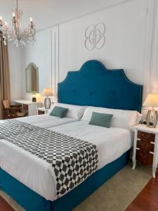 a large bed with a blue headboard in a bedroom at Hotel Derby Sevilla in Seville