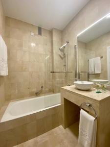 a bathroom with a tub and a sink and a bath tub at Hotel Derby Sevilla in Seville
