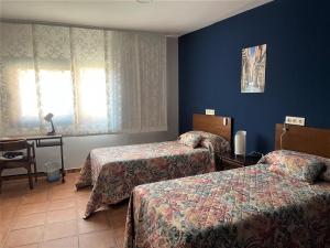 a hotel room with two beds and a table at B&B Puente de Órbigo in Hospital de Órbigo