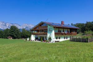 ein großes Haus auf einem Hügel mit grünem Feld in der Unterkunft Ferienwohnungen Gästehaus Lärcheck in Berchtesgaden