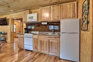 a kitchen with a white refrigerator and wooden cabinets at Cozy Creekside Cabin about 24 Mi to Red River! in Beattyville