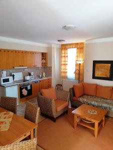 a living room with a couch and chairs and a kitchen at Daniella Apartman in Bükfürdő