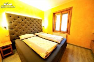 a bedroom with a bed with a padded headboard and a window at Residence Casa Longa in Livigno