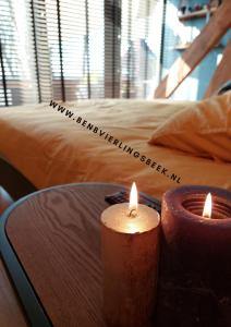 duas velas sentadas numa mesa em frente a uma cama em B&B Vierlingsbeek, Appartement Onder één dak en tuin-chalet em Vierlingsbeek