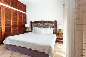 una camera da letto con un letto con lenzuola bianche e due lampade di Fabiola Condo Hotel a Playa del Carmen