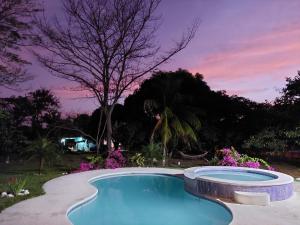 una piscina en un patio con puesta de sol en BEAUTIFUL HOUSE IN LAS UVAS SAN CARLOS, PANAMA WITH FRUIT TREES -SWIMMING POOL en Las Uvas